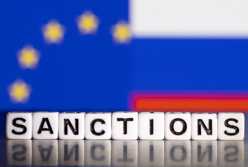 Illustration shows letters arranged to read "Sanctions" in front of flag colors of EU and Russia